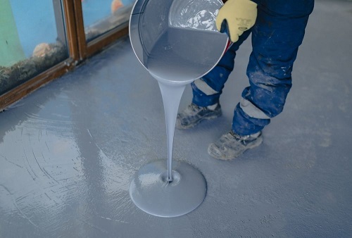 a worker pouring epoxy resin on the ground